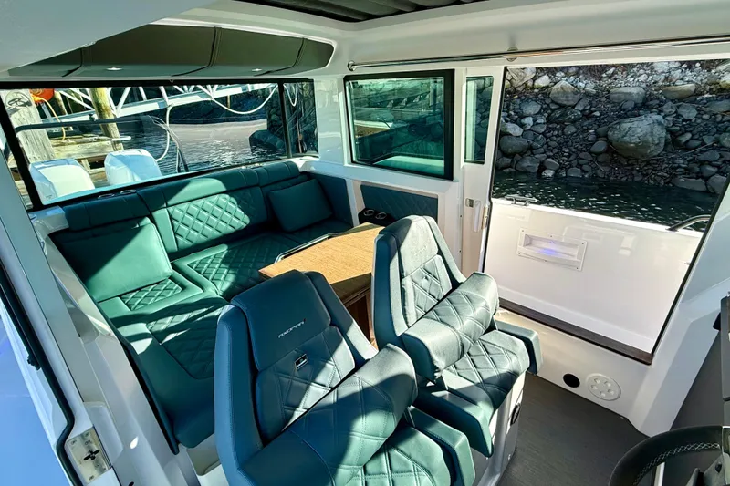 Slide: The Image of 2023 Axopar 37 Cross Cabin interior with luxurious seating and table, dockside view. - 25