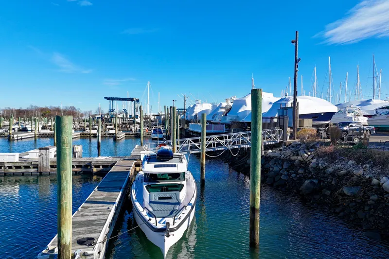 Slide: The Image of 2023 Axopar 37 Cross Cabin docked at a marina under clear blue skies. - 4