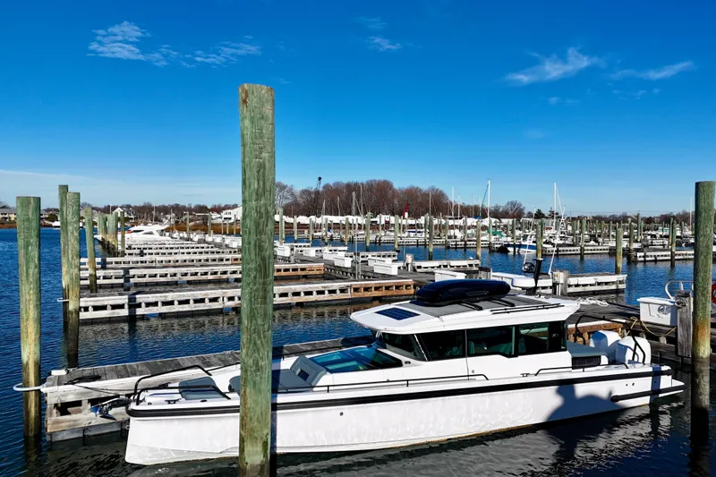 Slide: The Image of 2023 Axopar 37 Cross Cabin docked in a marina under a clear blue sky. - 5