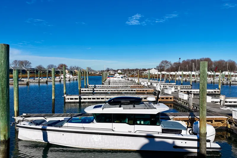 Slide: The Image of 2023 Axopar 37 Cross Cabin docked in a serene marina under a clear blue sky. - 6