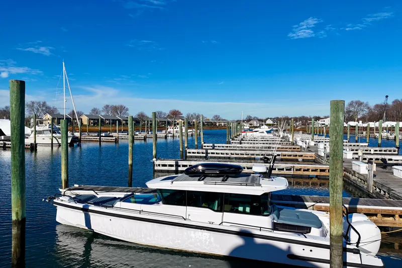 Slide: The Image of 2023 Axopar 37 Cross Cabin docked in a serene marina under a clear blue sky. - 7
