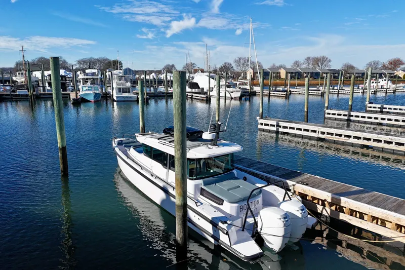 Slide: The Image of 2023 Axopar 37 Cross Cabin boat docked in a marina under clear blue skies. - 8