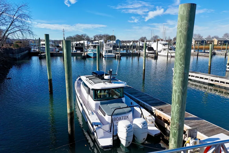 Slide: The Image of 2023 Axopar 37 Cross Cabin docked in a marina under a clear blue sky. - 9