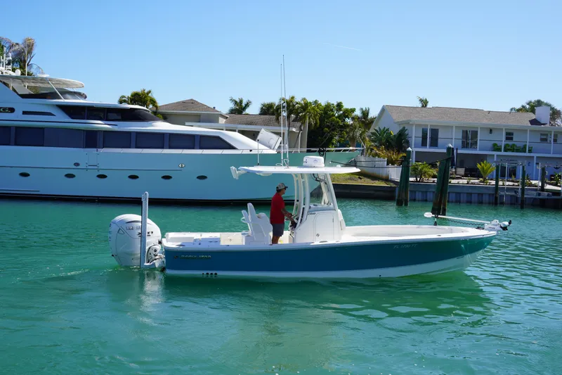 Slide: The Image of 2024 Regulator 26XO boat cruising in a sunny marina with luxury yachts nearby. - 10