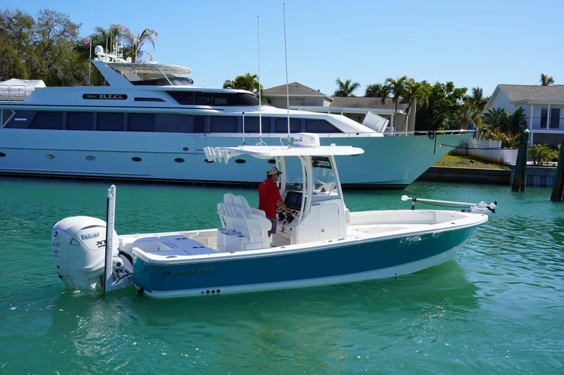 Slide: The Image of 2024 Regulator 26XO boat on turquoise water, with a large yacht in the background. - 12