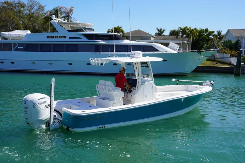 Slide: The Image of 2024 Regulator 26XO boat cruising in a marina with luxury yacht in background. - 13