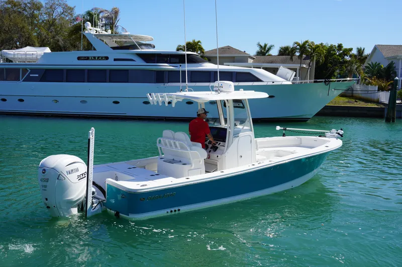 Slide: The Image of 2024 Regulator 26XO boat cruising in a marina with a luxury yacht in the background. - 14