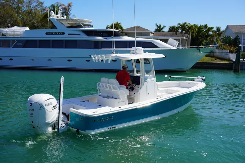 Slide: The Image of 2024 Regulator 26XO boat cruising in clear turquoise water near a large yacht. - 15