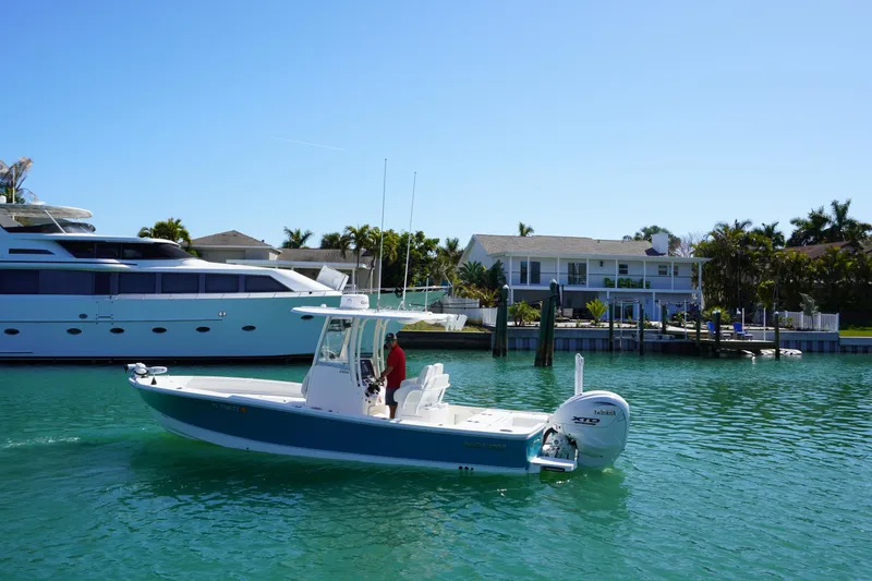 Slide: The Image of 2024 Regulator 26XO boat cruising in a sunny waterfront setting with luxury homes. - 21