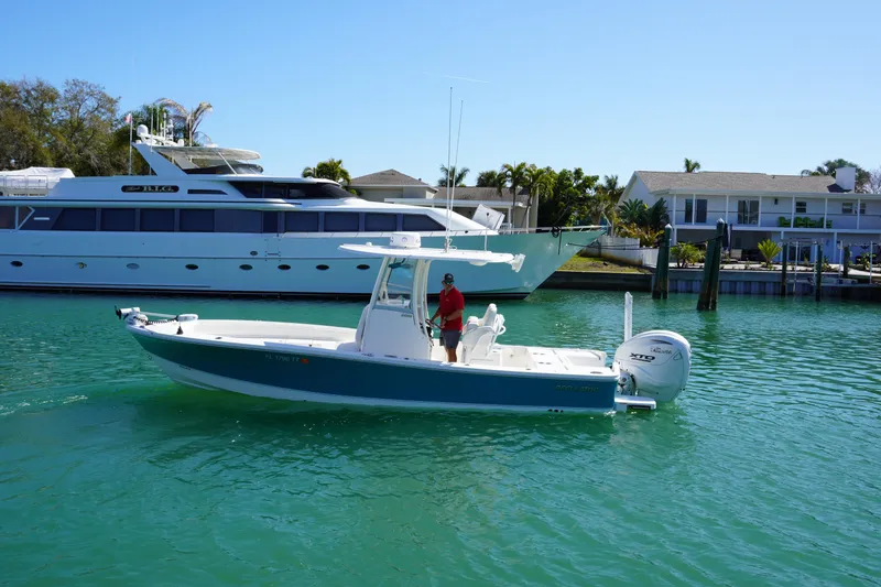 Slide: The Image of 2024 Regulator 26XO boat cruising in a sunny marina with luxury yachts and waterfront homes. - 22