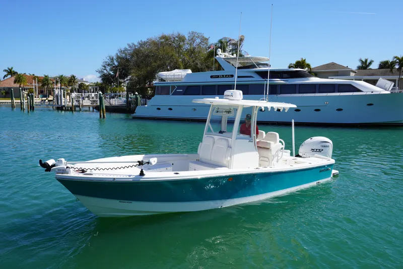 Slide: The Image of 2024 Regulator 26XO boat on turquoise water, docked near luxury yachts. - 24