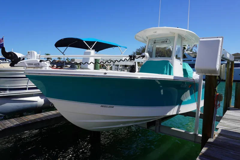 Slide: The Image of 2024 Regulator 26XO boat docked, featuring a sleek turquoise hull and modern design. - 27