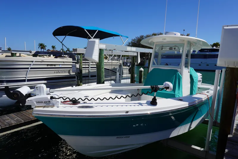 Slide: The Image of 2024 Regulator 26XO boat docked with Minn Kota trolling motor, turquoise cover, and sunny marina backdrop. - 28