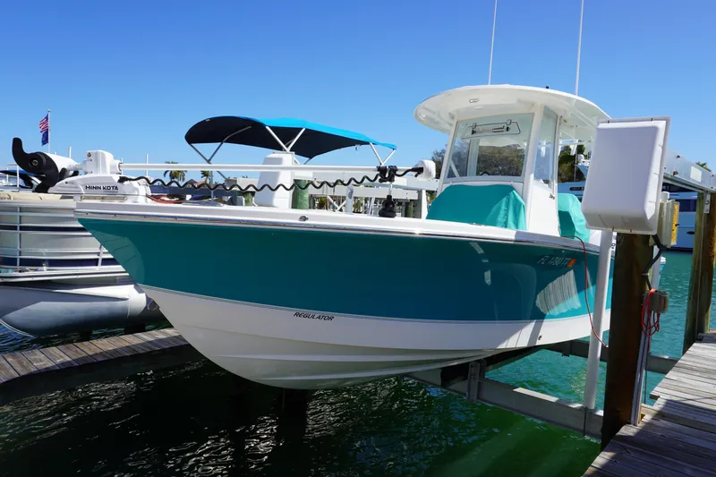 Slide: The Image of 2024 Regulator 26XO boat docked, featuring a sleek turquoise hull and modern design. - 29