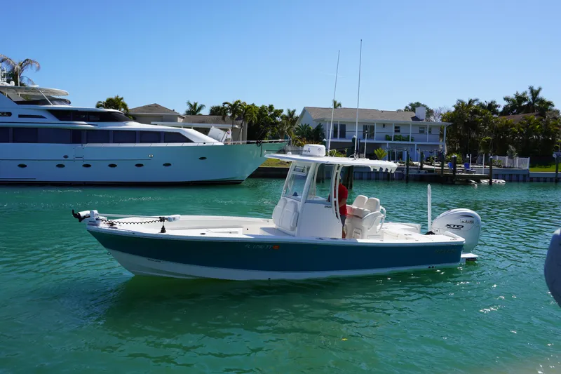 Slide: The Image of 2024 Regulator 26XO boat cruising in a sunny marina with luxury yachts nearby. - 3