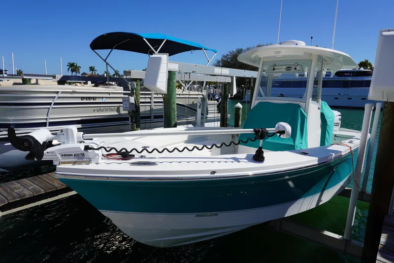 Slide: The Image of 2024 Regulator 26XO boat docked, featuring Minn Kota trolling motor, turquoise accents, and sunny marina setting. - 39