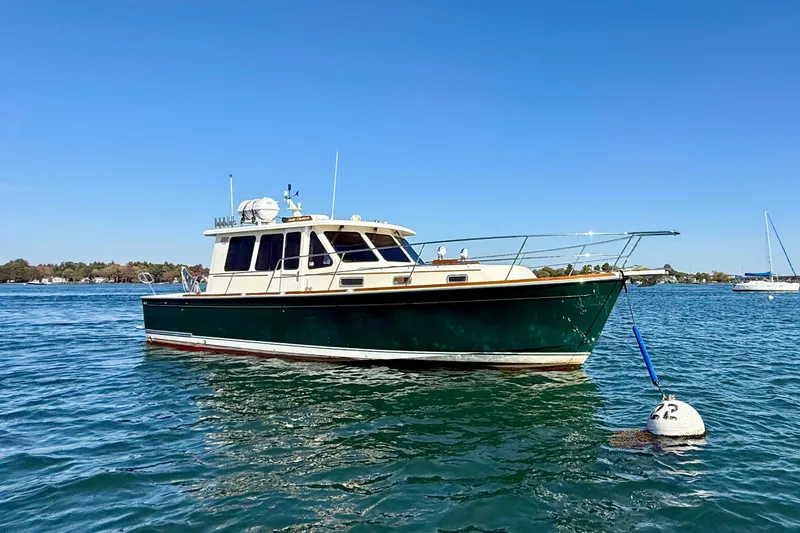 The Image of 2006 Sabre 42 Sedan boat anchored on calm water under clear blue sky. - 0