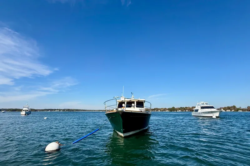 Slide: The Image of 2006 Sabre 42 Sedan yacht anchored on a clear blue lake under a sunny sky. - 4
