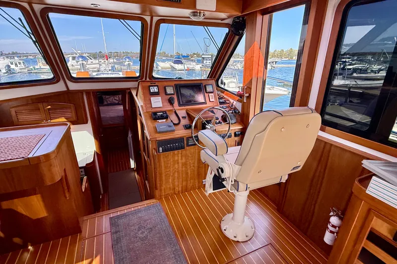 Slide: The Image of Interior of 2006 Sabre 42 Sedan yacht with helm, wooden finish, and marina view. - 43