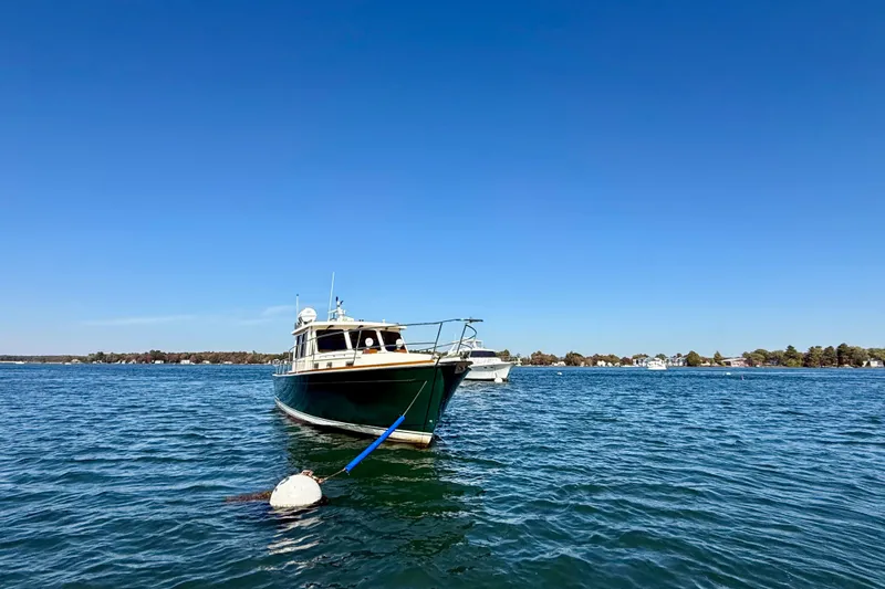 Slide: The Image of 2006 Sabre 42 Sedan boat moored on a calm lake under clear blue skies. - 5