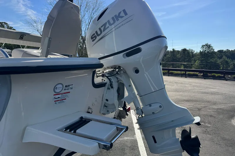 Slide: The Image of 2026 Carolina Skiff 19 LS with Suzuki outboard motor in a parking lot. - 2