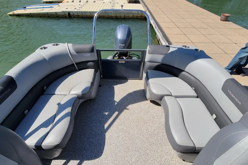 Slide: The Image of 2023 Veranda Relax VR20RC pontoon boat interior with gray seating and dock view. - 8