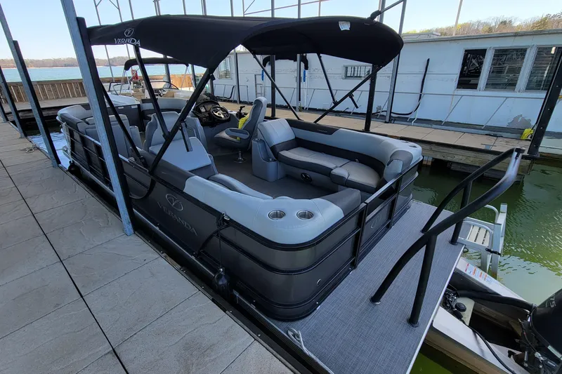 Slide: The Image of 2023 Veranda Relax VR22RC pontoon boat docked, featuring spacious seating and sleek design. - 2