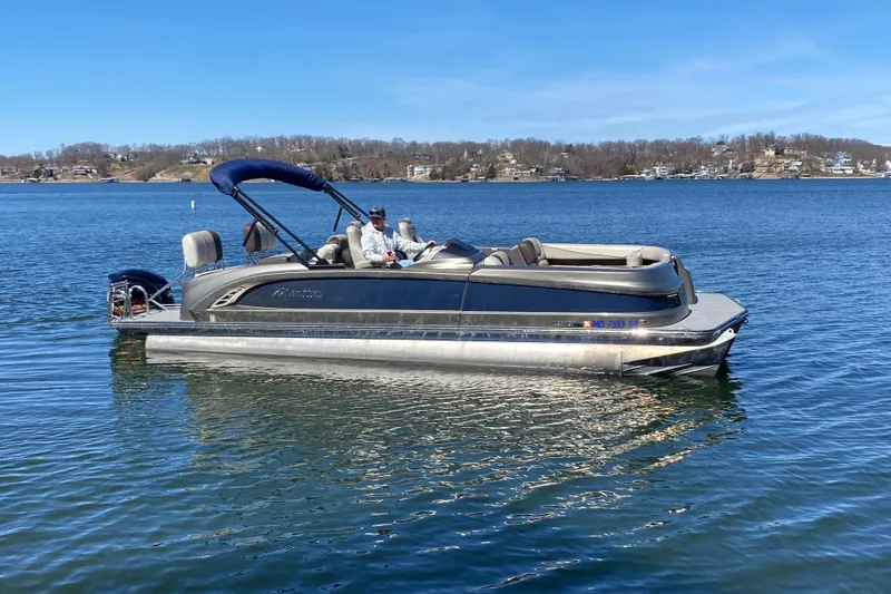 The Image of 2016 Manitou 25 Legacy LT SHP pontoon boat on a serene lake. - 1