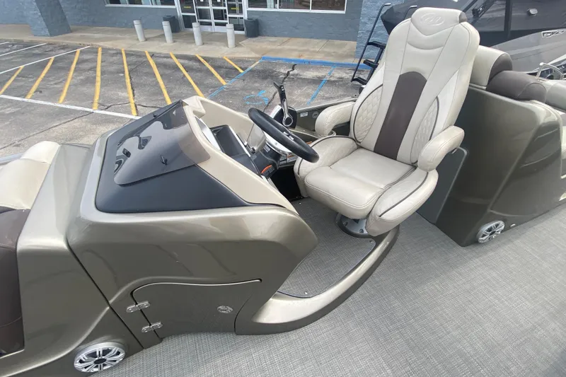 Slide: The Image of 2016 Manitou 25 Legacy LT SHP boat interior with captain's chair and steering console. - 15