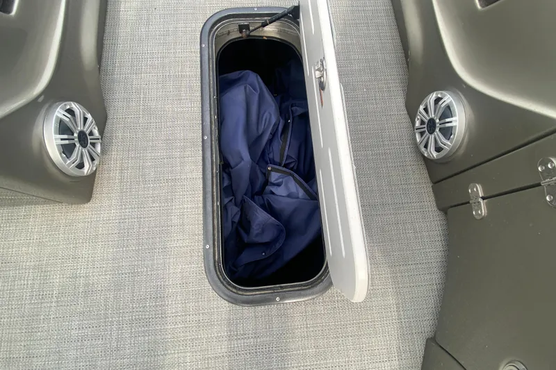 Slide: The Image of Open storage compartment on 2016 Manitou 25 Legacy LT SHP boat with speakers visible. - 18