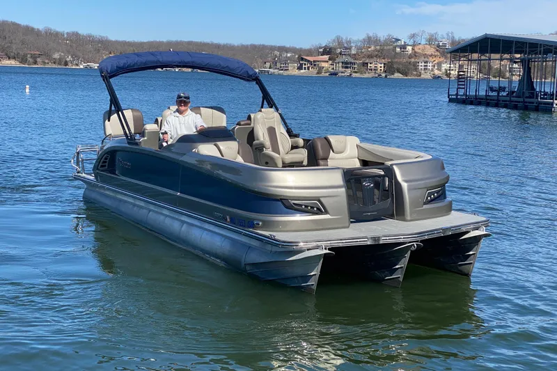 Slide: The Image of 2016 Manitou 25 Legacy LT SHP pontoon boat on a lake with a person driving. - 4