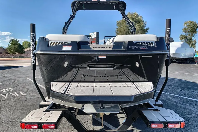 Slide: The Image of 2026 Moomba Mojo boat on trailer, rear view, black exterior, sunny day. - 4