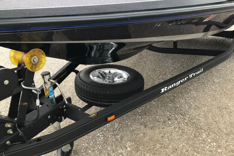 Slide: The Image of 2022 Ranger Z185 boat trailer with spare tire on gravel surface. - 16