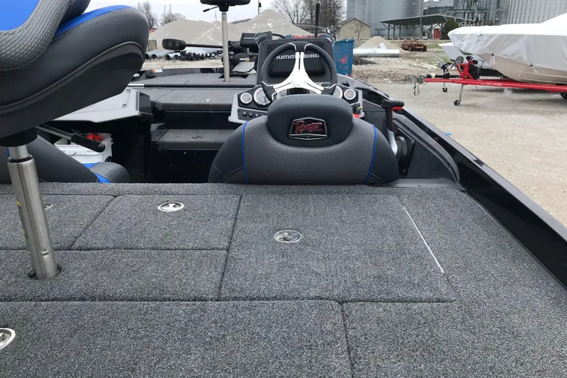 Slide: The Image of 2022 Ranger Z185 boat interior with gray carpet and seating, parked outdoors. - 28