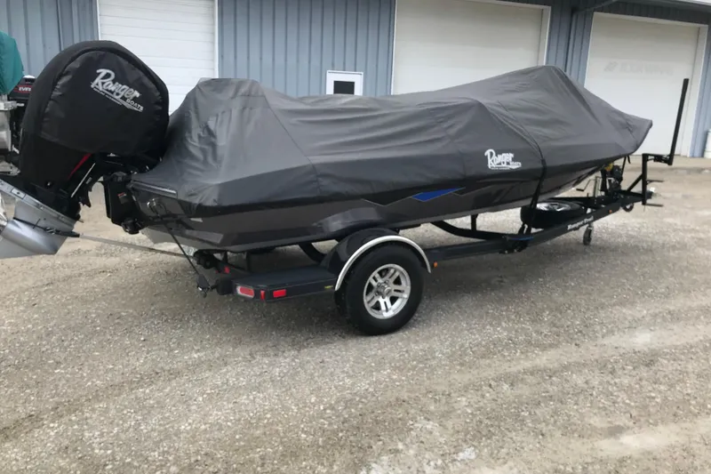 Slide: The Image of 2022 Ranger Z185 boat covered on trailer, parked outside a garage. - 43