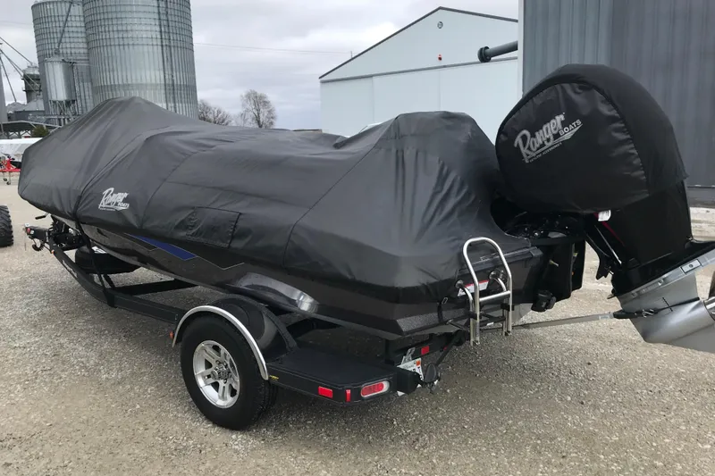 Slide: The Image of 2022 Ranger Z185 boat covered, parked on trailer near industrial buildings. - 45