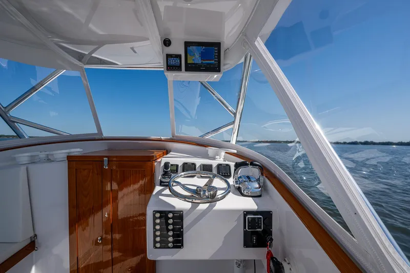 Slide: The Image of 2019 Custom Carolina Custom Express boat helm with navigation system, steering wheel, and ocean view. - 10
