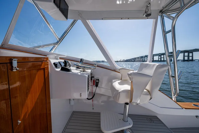 Slide: The Image of 2019 Custom Carolina Custom Express boat interior with helm, white seating, and ocean view. - 12