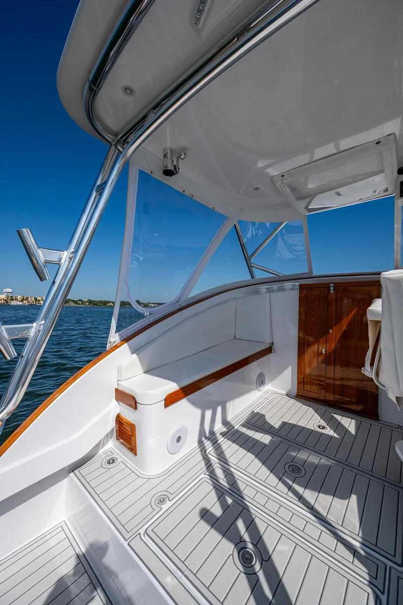 Slide: The Image of 2019 Custom Carolina Custom Express boat deck with seating, wood accents, and ocean view. - 17