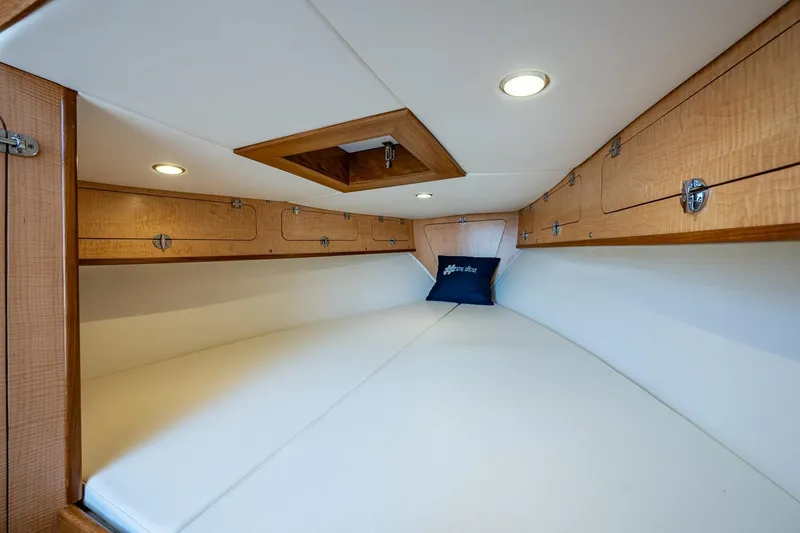 Slide: The Image of 2019 Custom Carolina Custom Express cabin interior with wood accents and white bedding. - 19