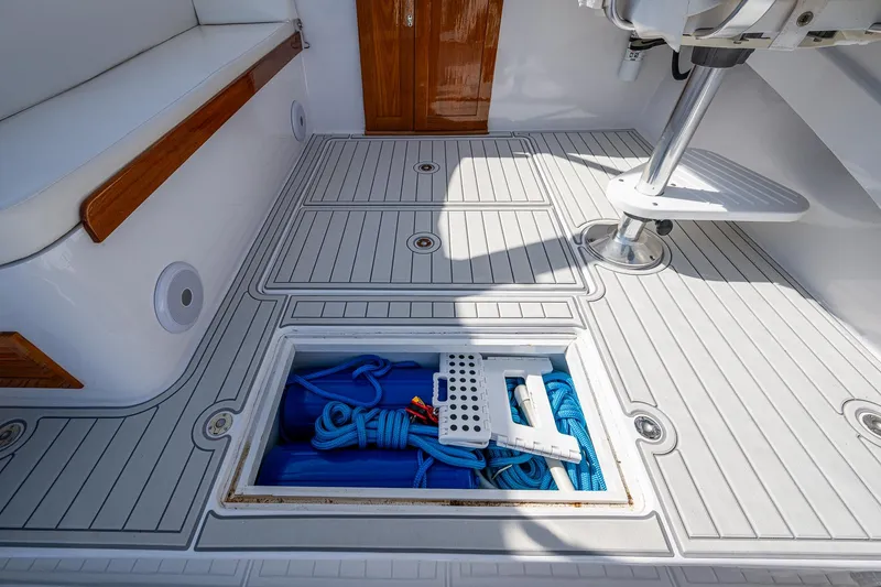 Slide: The Image of 2019 Custom Carolina Custom Express boat deck with storage compartment open, revealing blue ropes. - 24