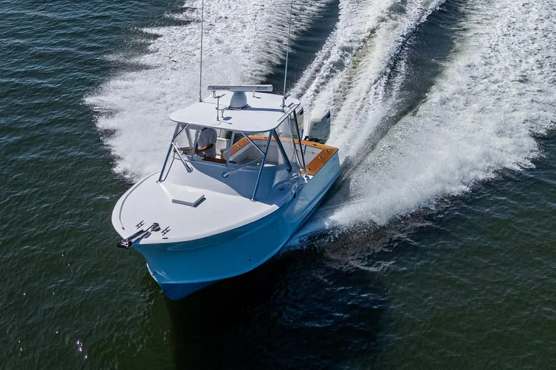 Slide: The Image of 2019 Custom Carolina Custom Express boat cruising on open water, creating a dynamic wake. - 5