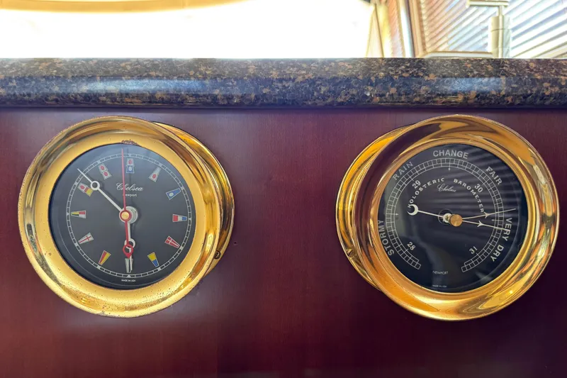 Slide: The Image of Gold-trimmed clock and barometer on 2005 Sea Ray 550 Sedan Bridge yacht dashboard. - 34