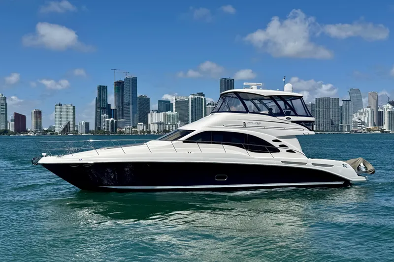Slide: The Image of 2005 Sea Ray 550 Sedan Bridge yacht on water with city skyline backdrop. - 5
