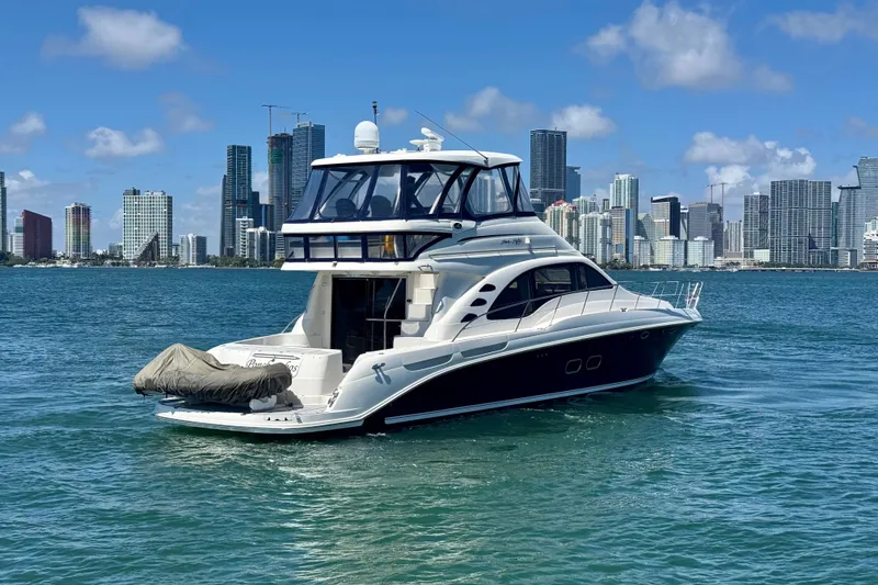 Slide: The Image of 2005 Sea Ray 550 Sedan Bridge yacht on water with city skyline backdrop. - 9