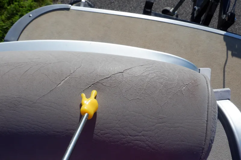 Slide: The Image of Cracked upholstery on 2009 Premier 225 Sunsation LTD boat seat with yellow tool. - 42