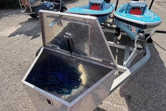 Slide: The Image of Open storage box with blue rope beside American Marine H:Skiff H13 boats on trailer. - 9