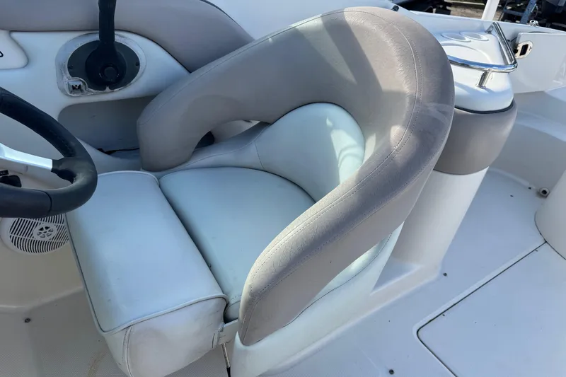 Slide: The Image of 2004 Sea Ray 240 Sundeck boat interior with steering wheel and cushioned seat. - 16
