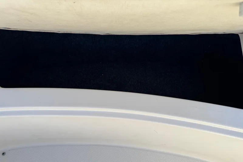 Slide: The Image of Interior view of a 2004 Sea Ray 240 Sundeck boat, featuring a dark carpeted area. - 26