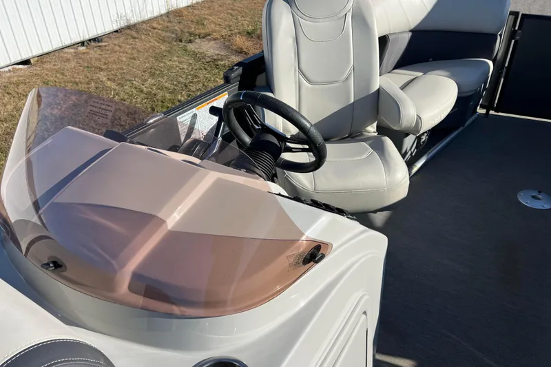 Slide: The Image of 2022 Sylvan Mirage X1 Tritoon boat interior with steering wheel and seating. - 22